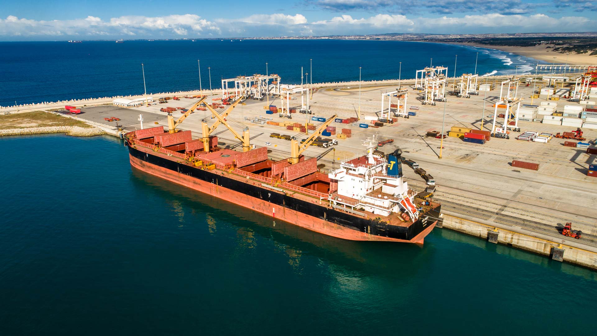 large cargo ship docked at a port with cranes unloading containers