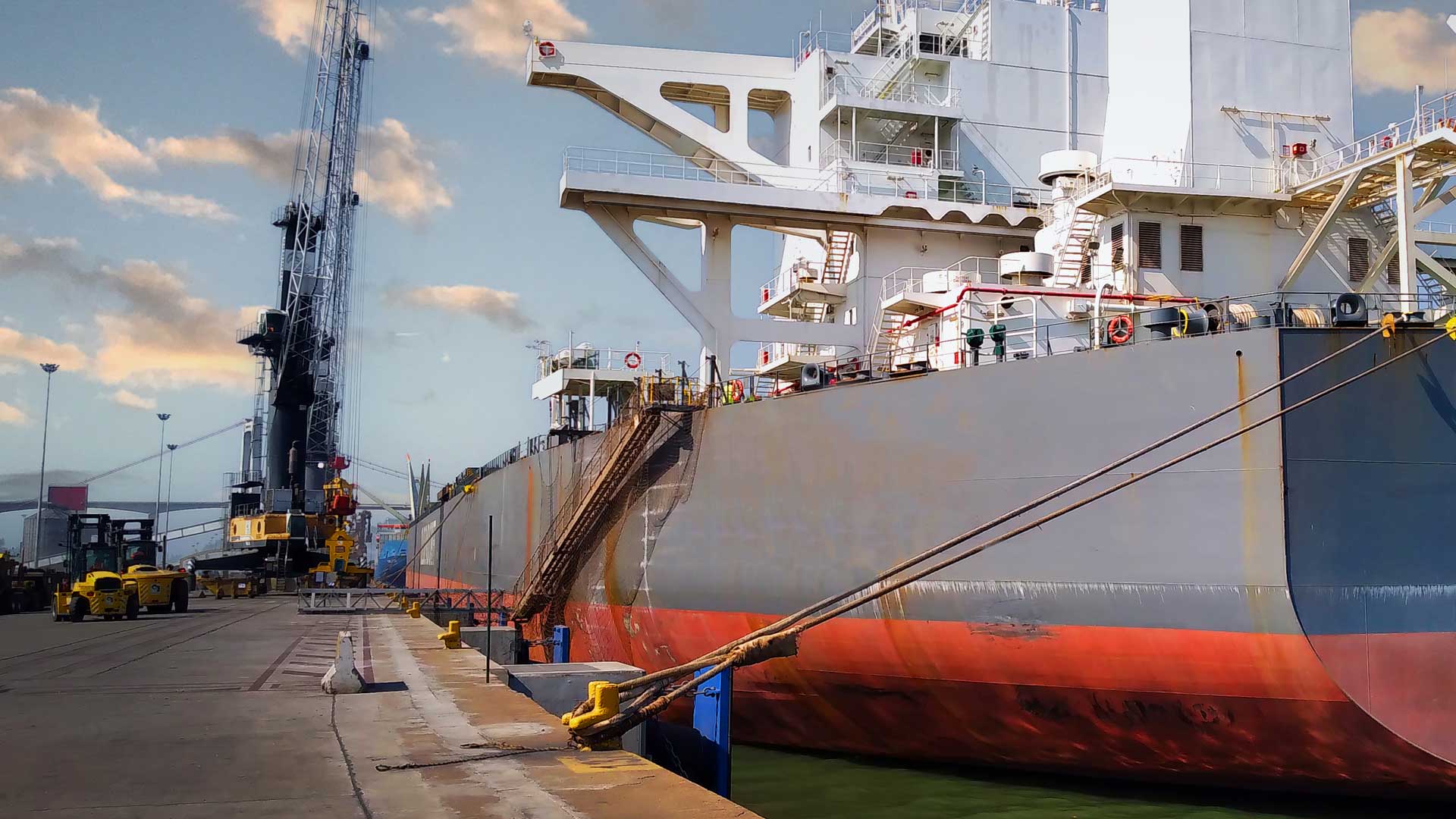 large cargo ship docked at a port, secured with ropes