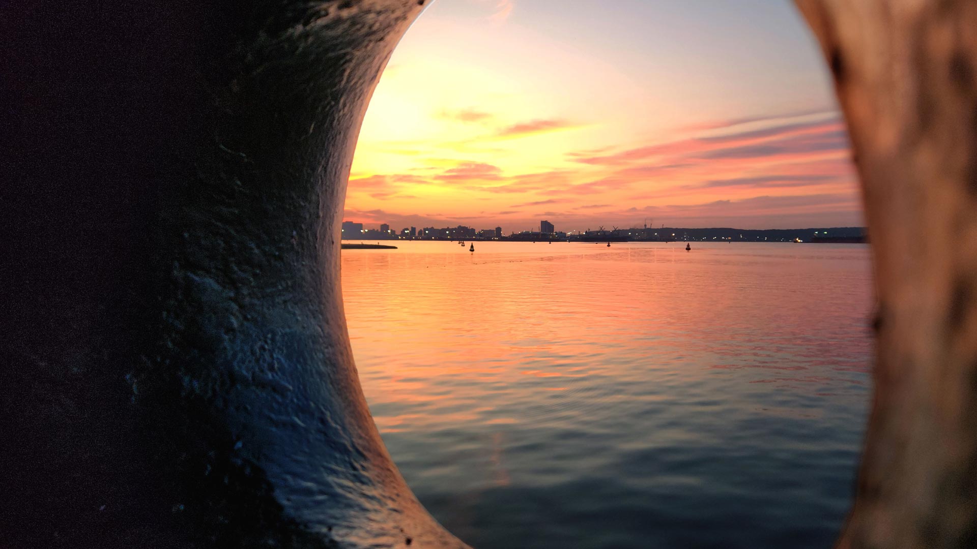 view of a calm body of water at sunset, framed by a circular opening