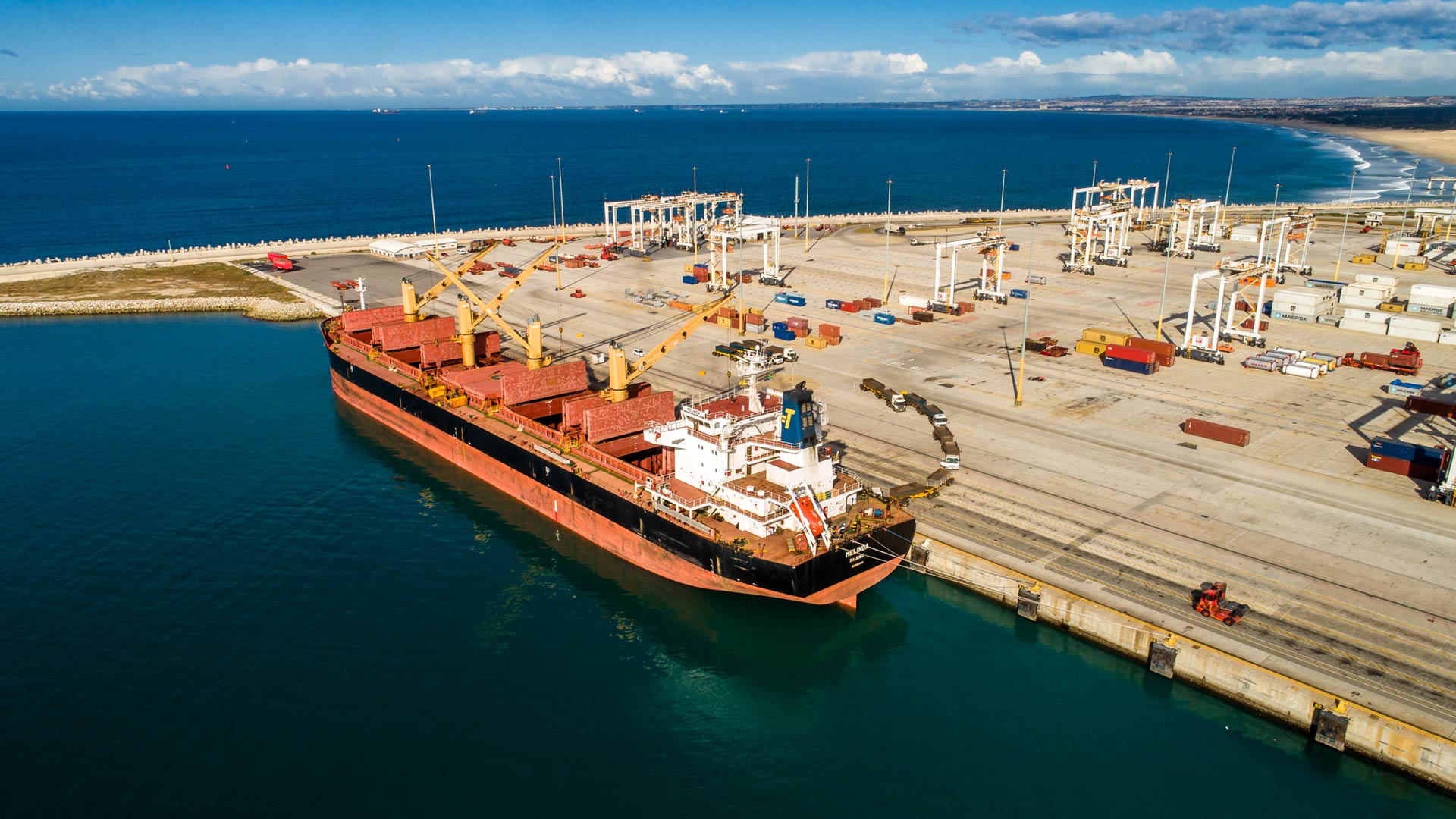 large cargo ship docked at a port with cranes unloading containers